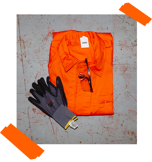 Équipement de sécurité pour la Smash Room : combinaison orange pliée, gants de travail et lunettes de protection sur fond gris.