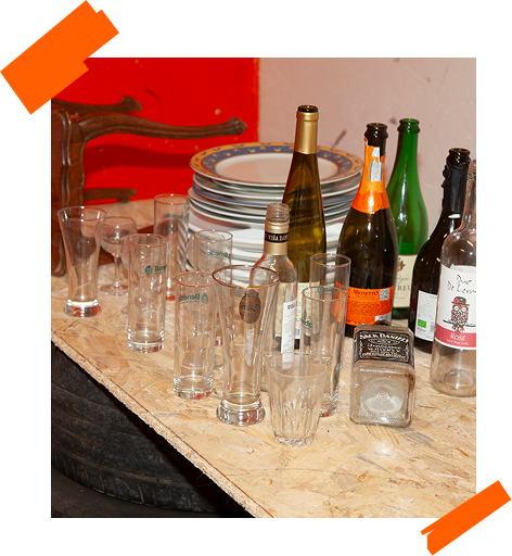 Pack Classic Smash : bouteilles en verre, verres et assiettes disposés sur une table en OSB.